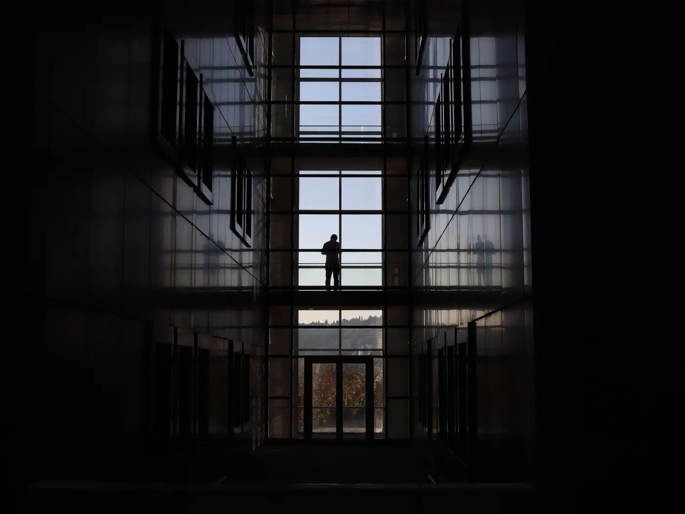 Person in der Glashalle eines Bürogebäudes, Blick über die Stadt
